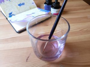 A painters pencil resting in a glass of water
